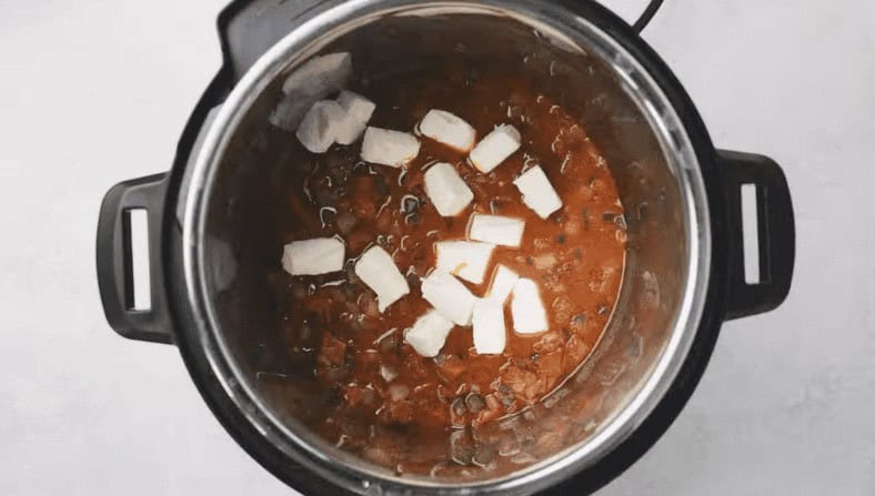 Cream cheese added to the Instant Pot with tomatoes and broth.  - 8