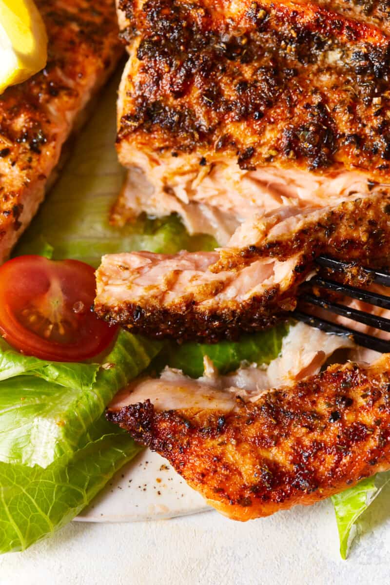 close up view of a piece of air fryer salmon being cut with a fork.