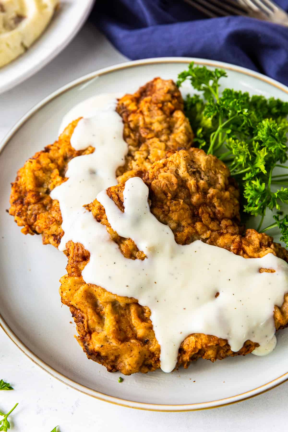 up close chicken fried steak with gravy on white plate