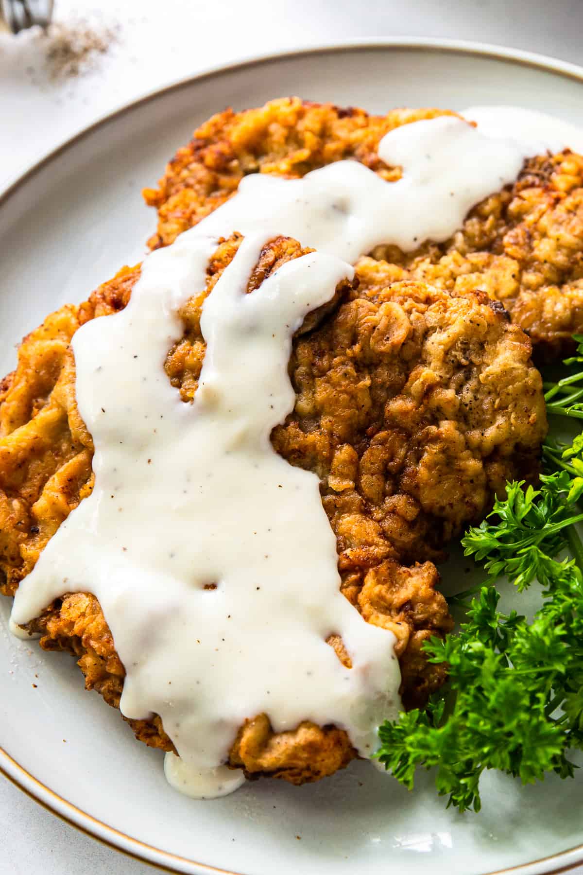 up close chicken fried steak with gravy on white plate