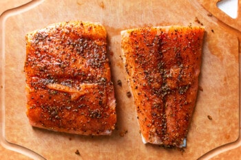 2 seasoned salmon filets on a cutting board.