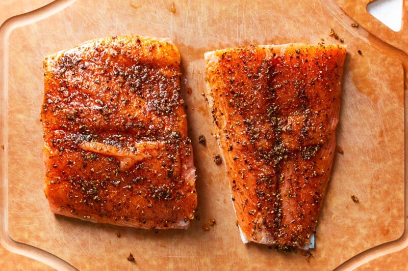 2 seasoned salmon filets on a cutting board.
