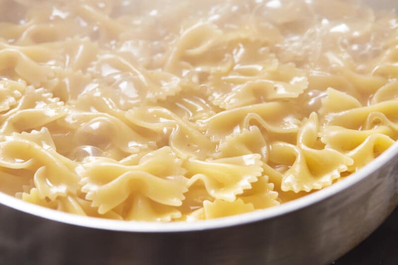 closeup of cooked bowtie pasta in a stainless steel pot.