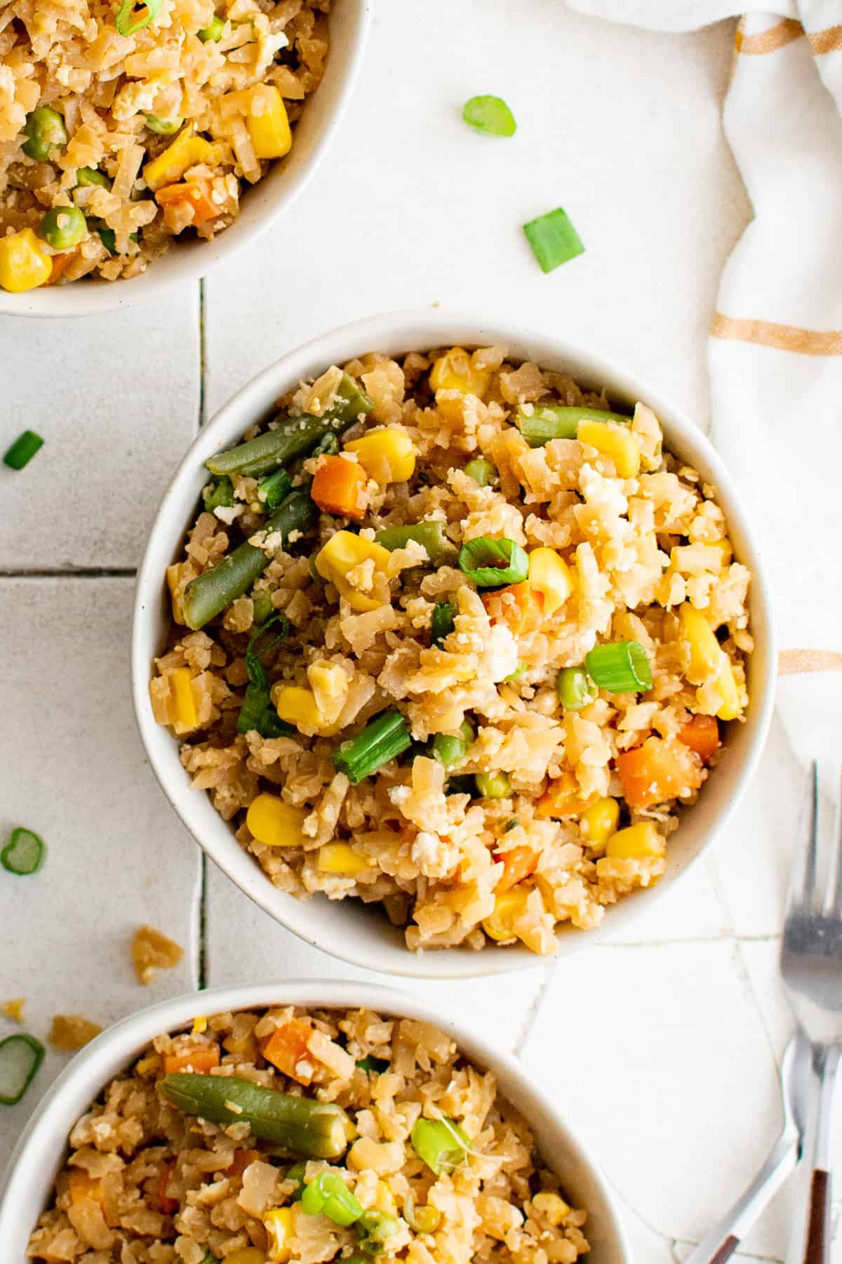 overhead view of cauliflower fried rice in white bowls.