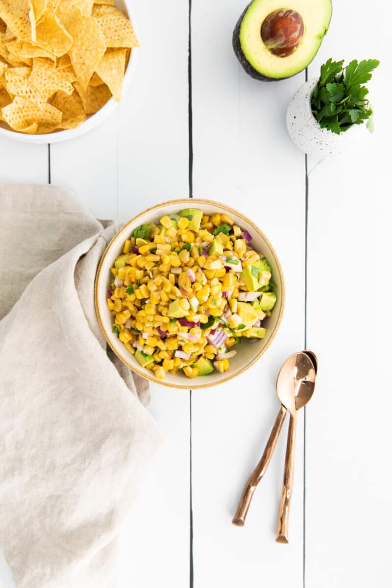 corn and avocado salsa in a white bowl with a spoon.