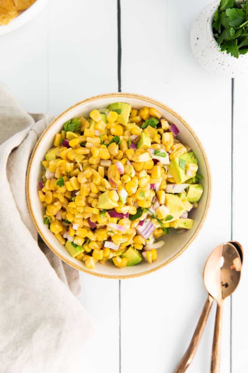 corn and avocado salsa in a white bowl with a spoon.