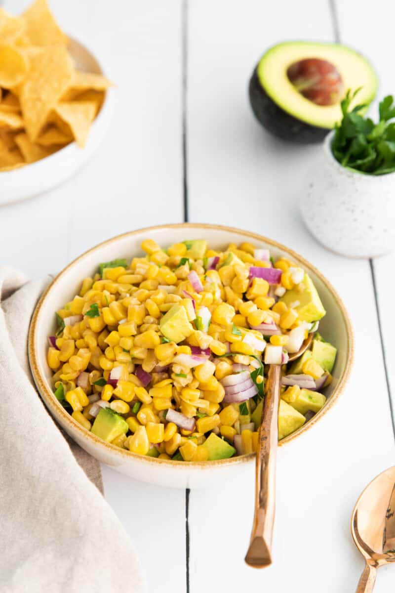 corn and avocado salsa in a white bowl with a spoon.