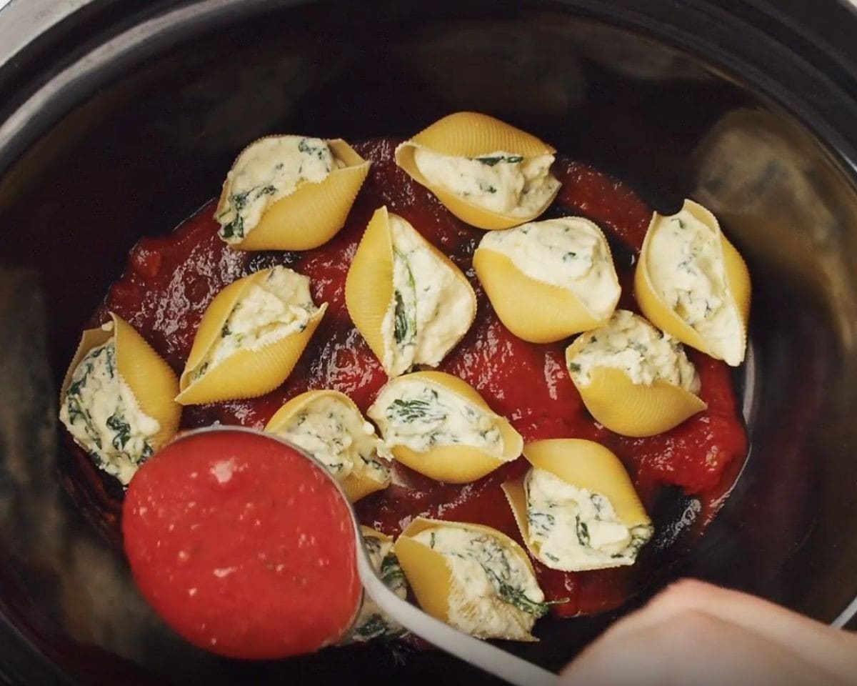 Layering the stuffed shells with sauce in the crockpot. - 8