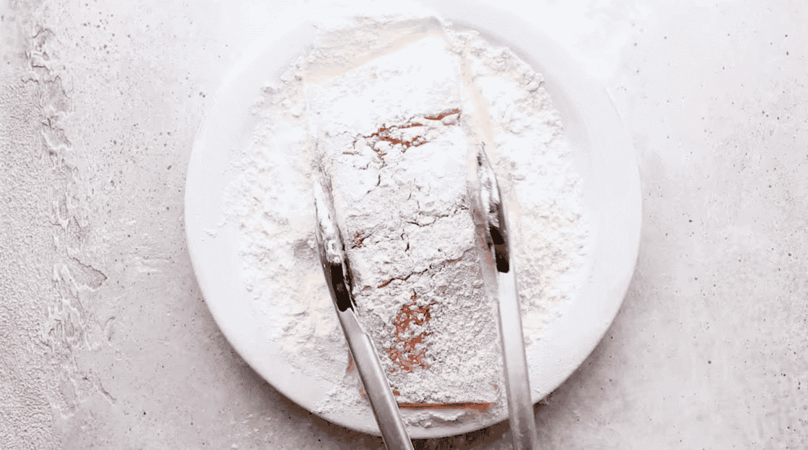 Dredging the salmon in flour with tongs.