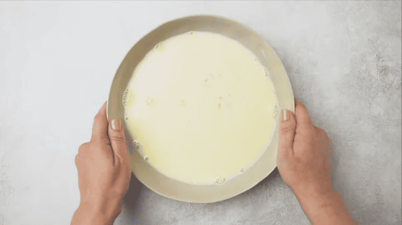 A person holding a bowl of white liquid, reminiscent of chicken fried steak.