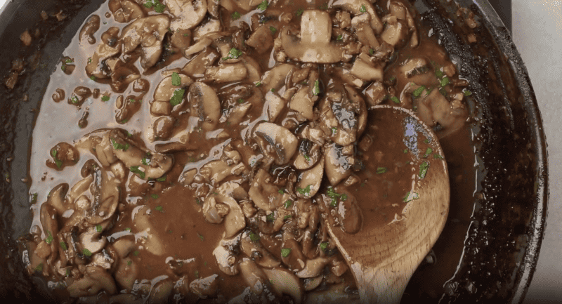 marsala sauce in a pan with a wooden spoon.