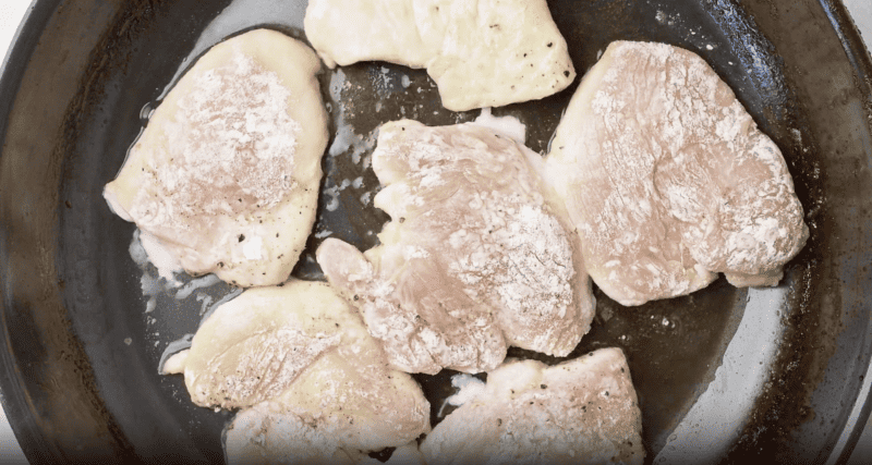 Chicken cutlets cooking in a pan.