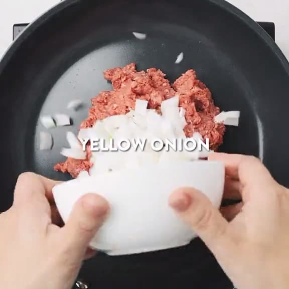 Putting ground beef and onions in a frying pan.