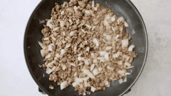 A frying pan filled with ground beef, onions, and Doritos for a casserole.