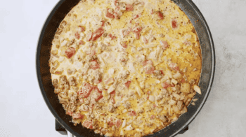 A skillet filled with a tomato, cheese, and Doritos casserole.