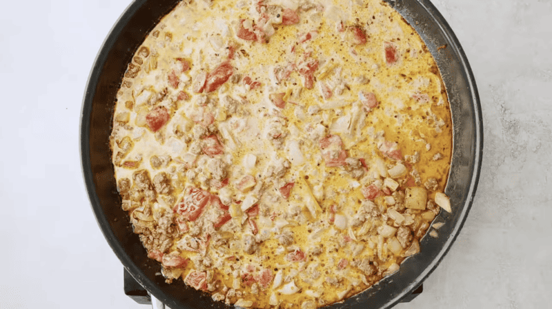 A skillet filled with a tomato, cheese, and Doritos casserole.