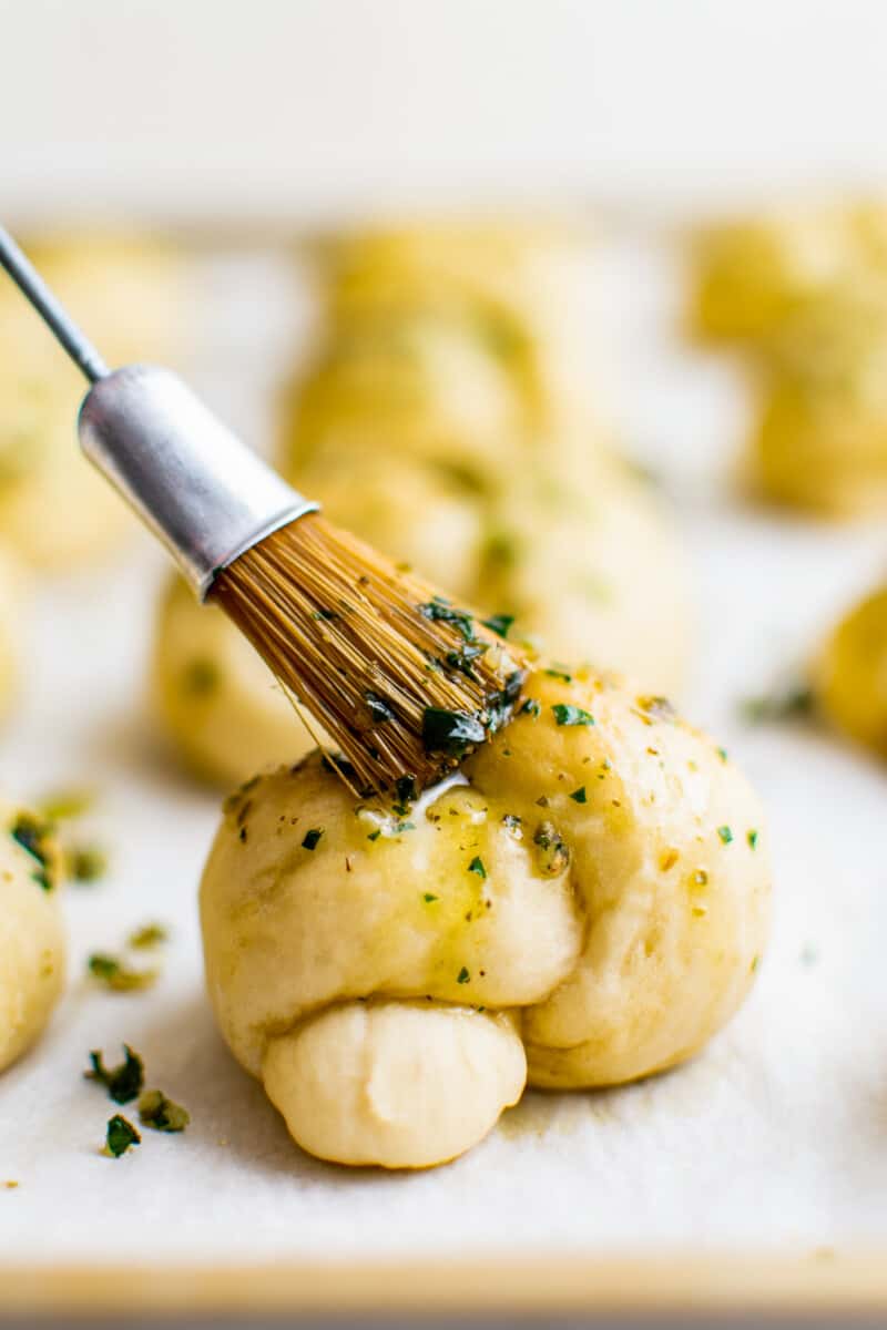 brushing garlic butter on garlic knots