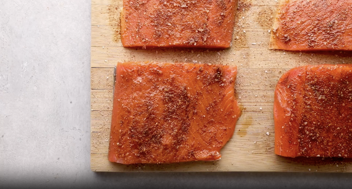 healthy seasoned salmon fillets on a wooden cutting board.