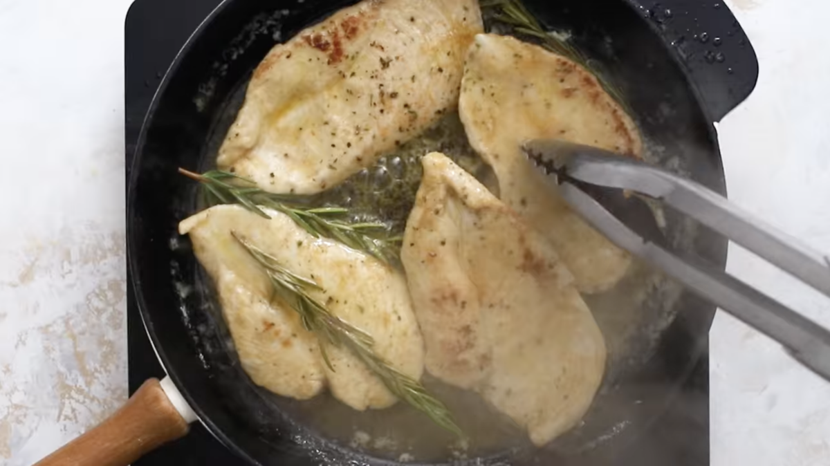4 lemon chicken breasts in a cast iron skillet with rosemary.