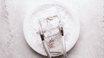 dredging a salmon fillet in flour with tongs.