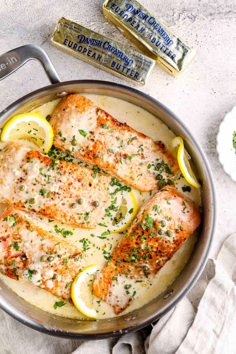 creamy salmon piccata in skillet with lemon slices