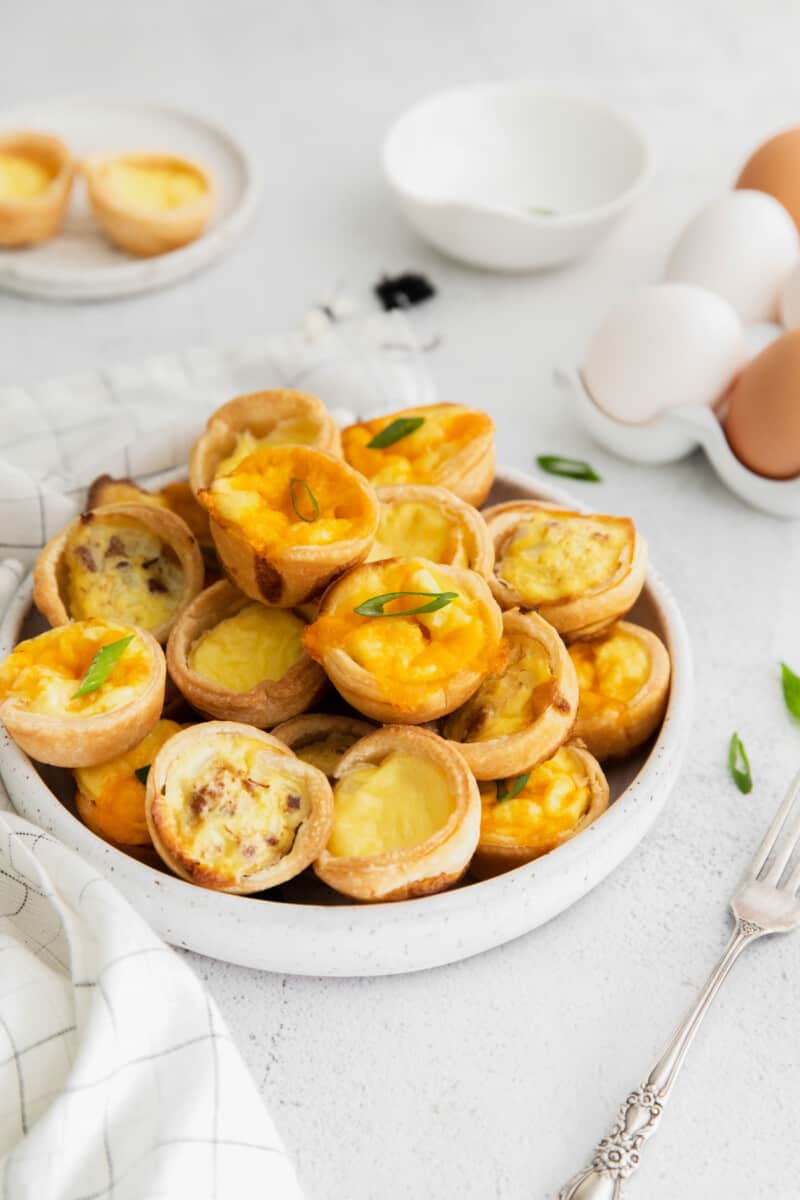 mini quiches stacked on a white plate.