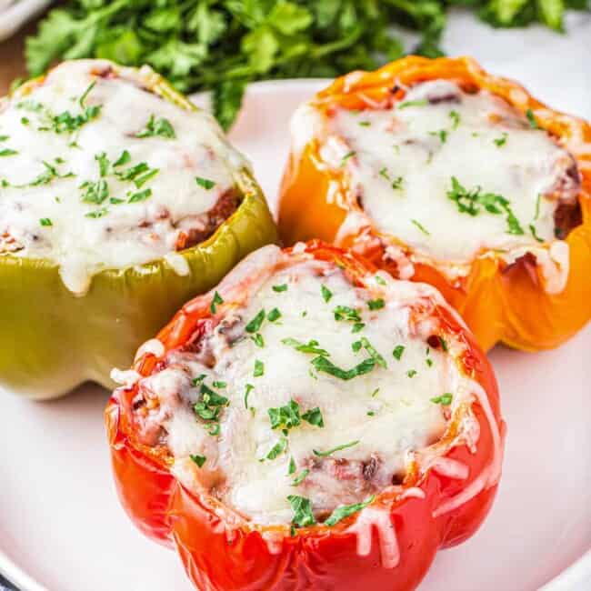 Three air fryer stuffed peppers on a white plate.