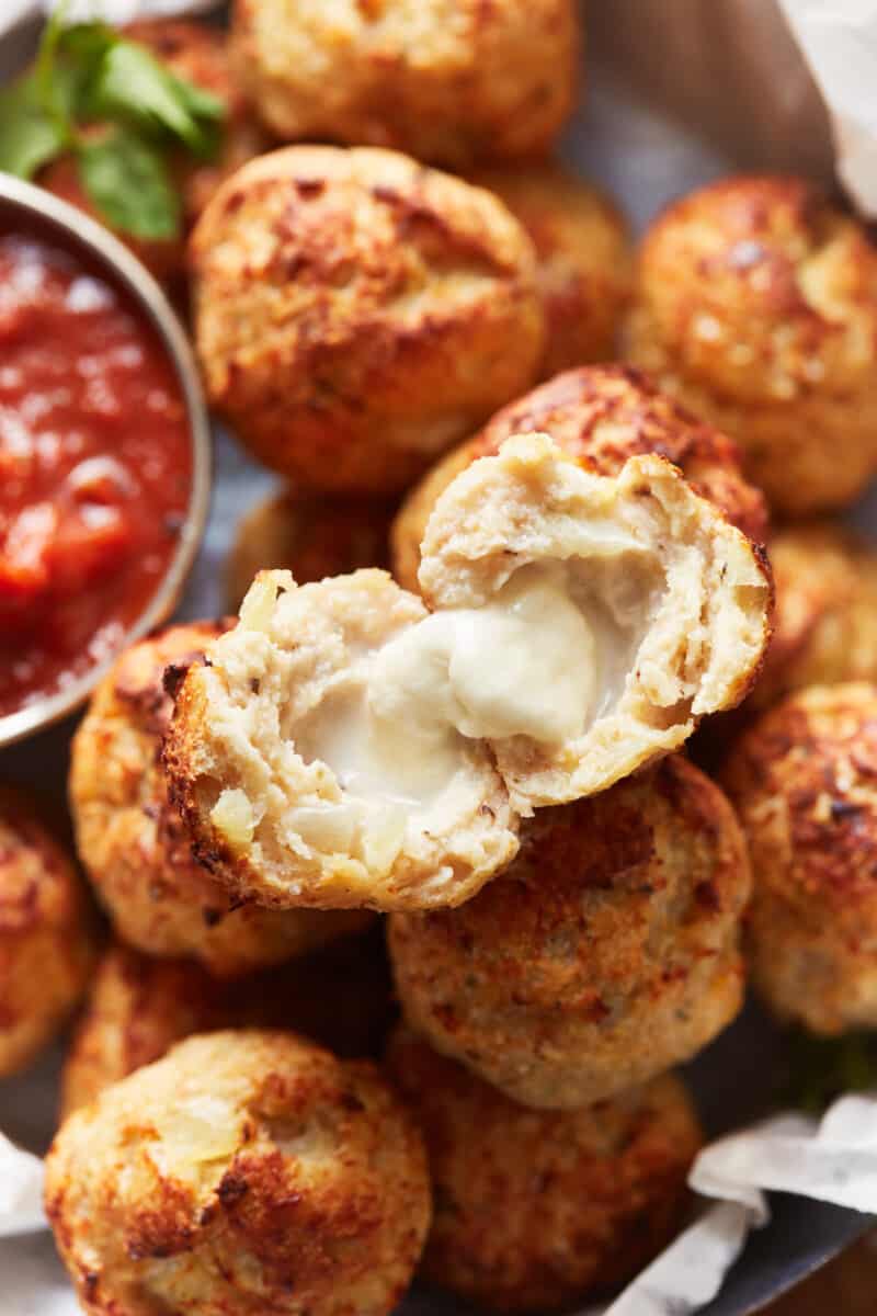 a halved baked turkey meatball on top of a pile of meatballs.