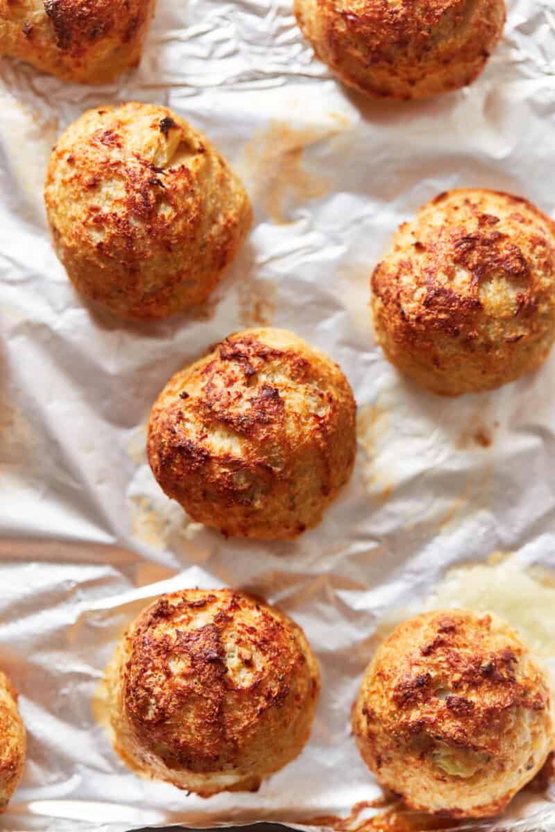 overhead view of 8 baked turkey meatballs on white parchment paper.