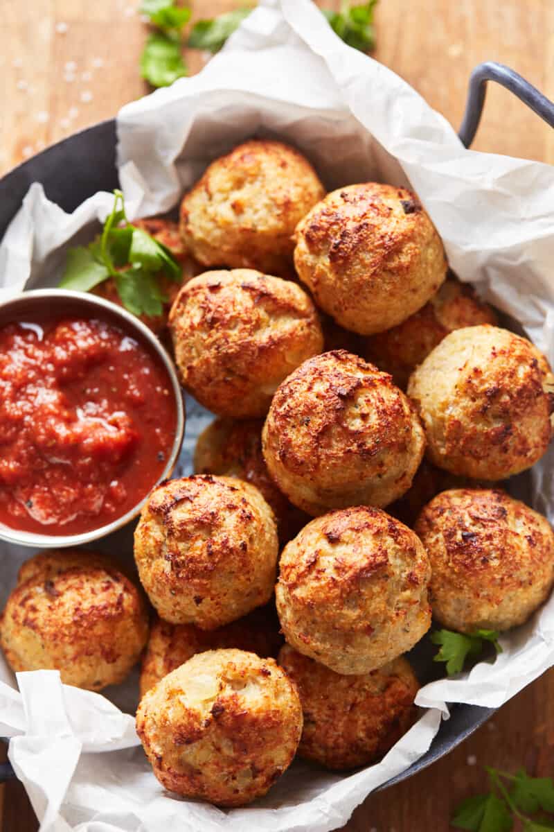 baked turkey meatballs in a basket with marinara sauce in a small cup.