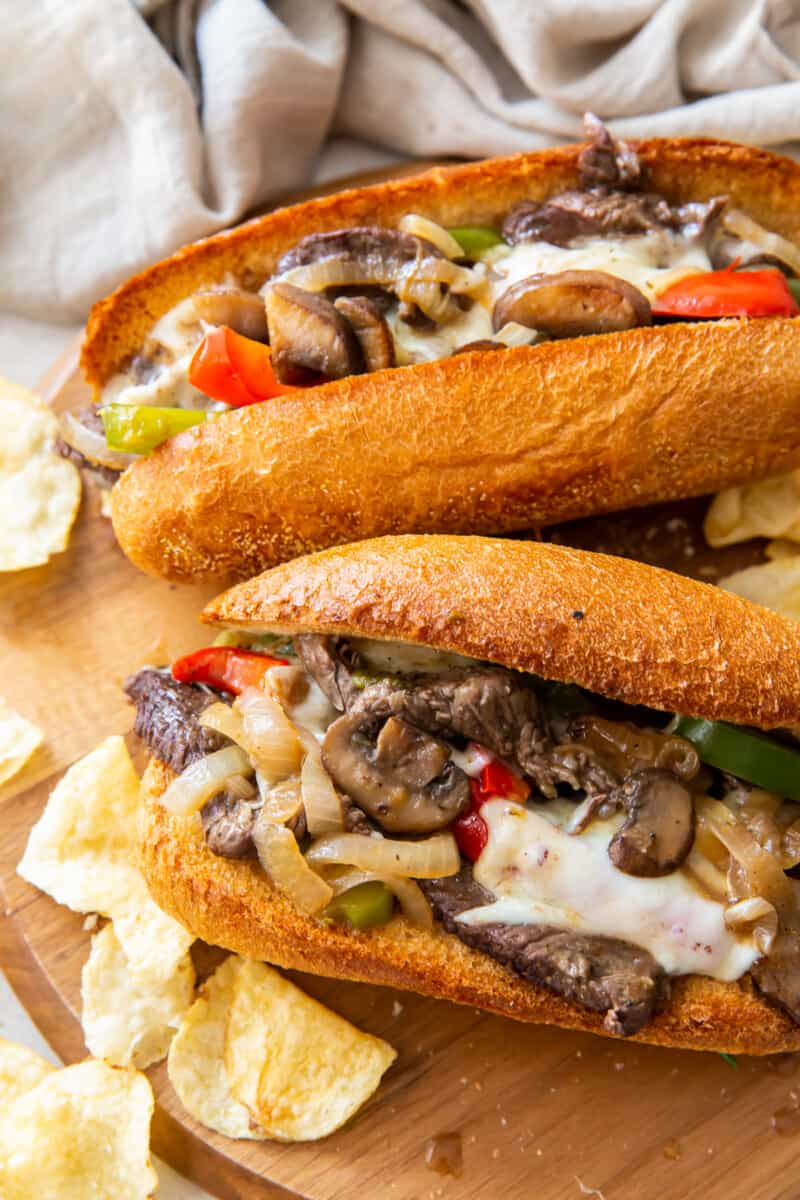 two philly cheesesteaks on cutting board