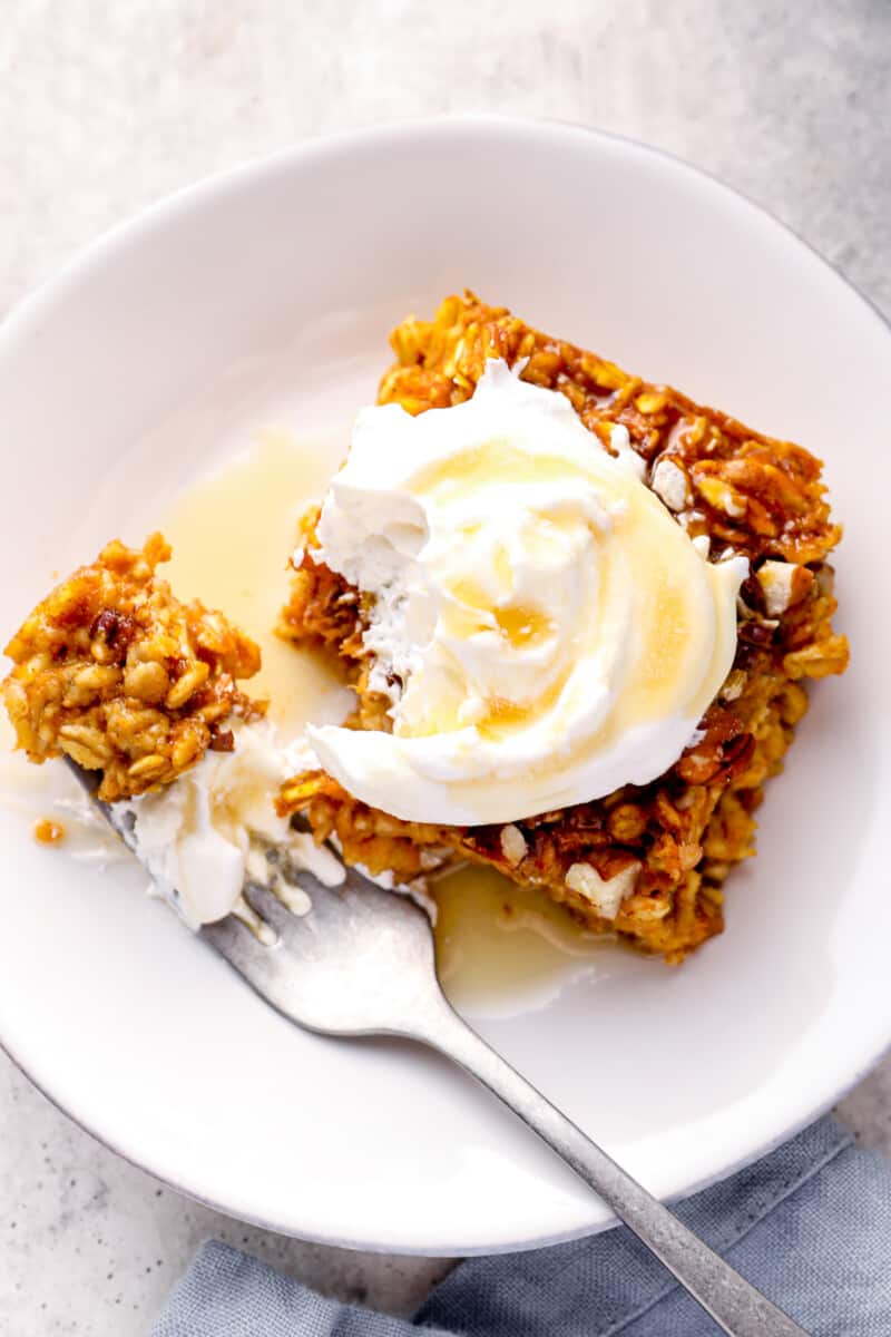 slice of pumpkin pie baked oatmeal with whipped cream and maple syrup