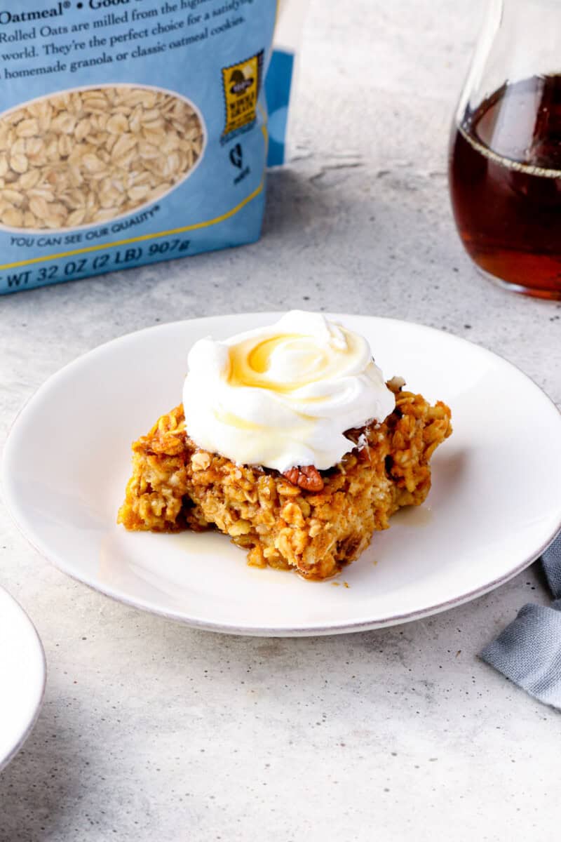 slice of pumpkin pie baked oatmeal with whipped cream and maple syrup