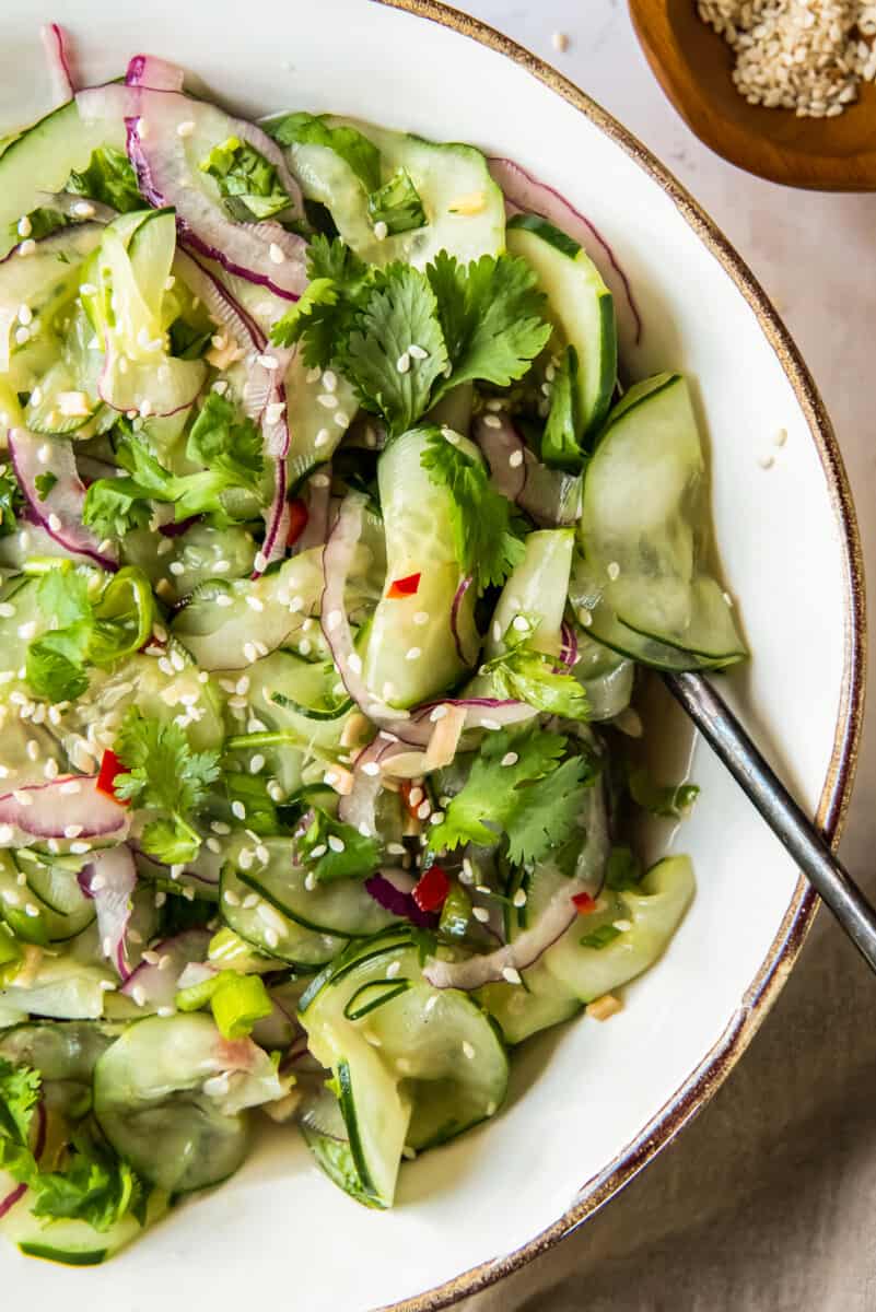 asian cucumber salad in white bowl with spoon