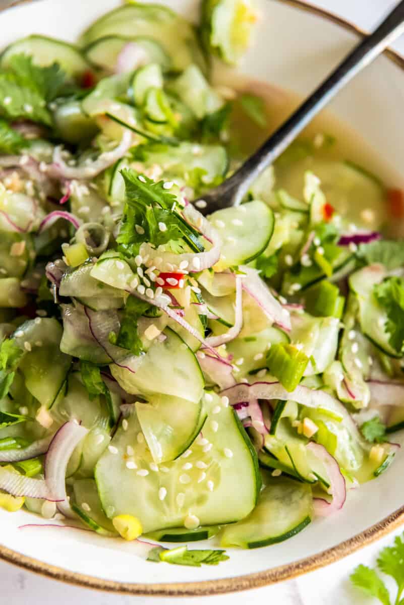 asian cucumber salad in white bowl with spoon