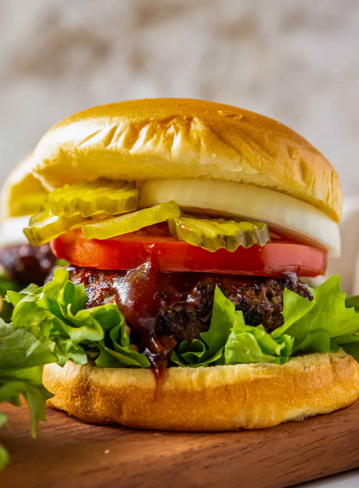 up close grilled bbq burgers with lettuce, tomato, onion, and pickles