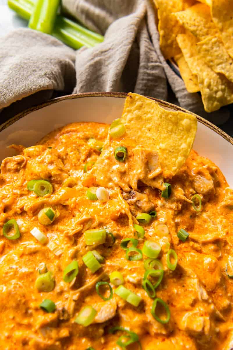 bowl of chips next to crockpot buffalo chicken dip