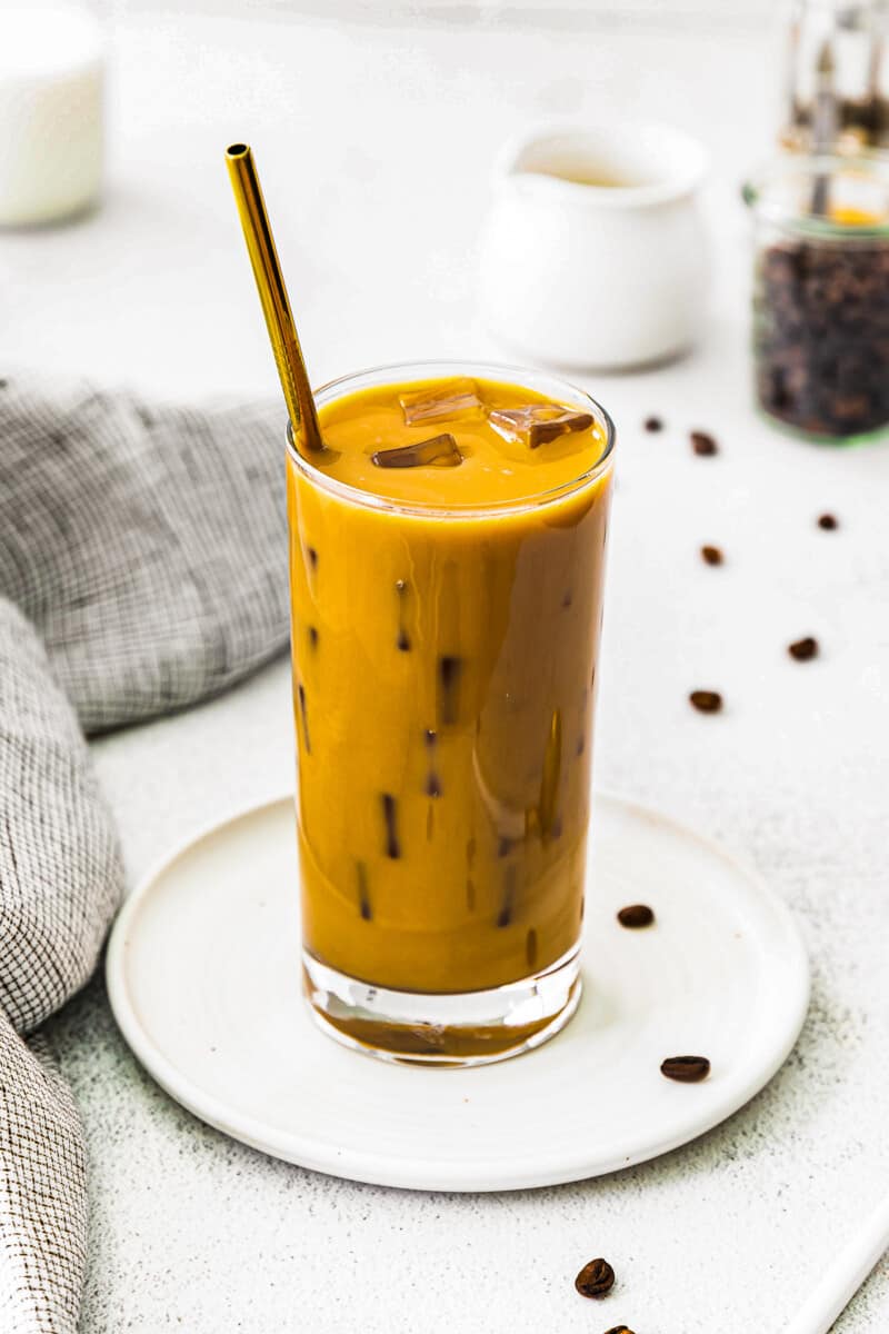 stirred iced caramel latte in glass with gold straw