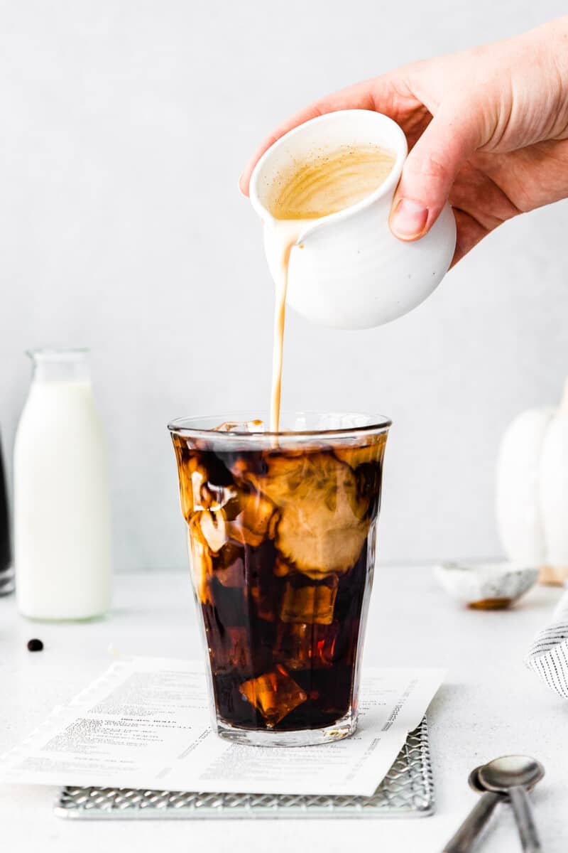 pouring pumpkin cream into cold brew