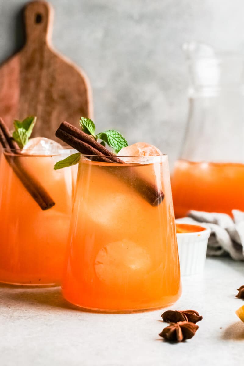 two glasses of pumpkin whiskey smash garnished with cinnamon sticks