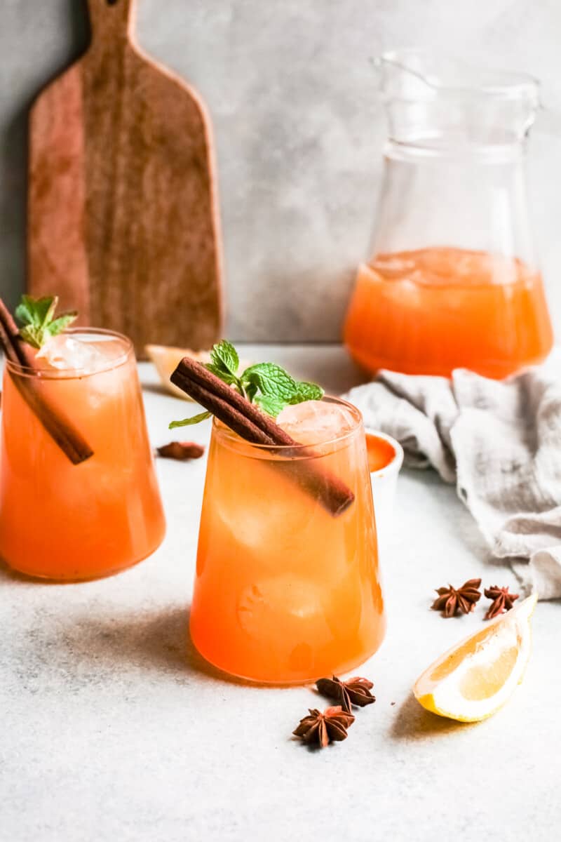 two glasses of pumpkin whiskey smash garnished with cinnamon sticks and mint