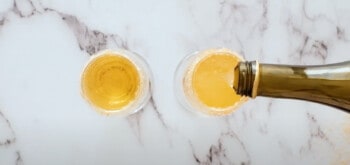 pouring champagne into a champagne flute filled with apple cider