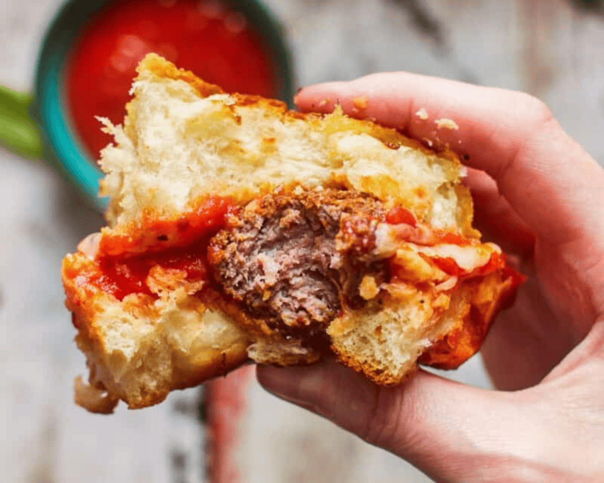 A bite taken out of a meatball slider.