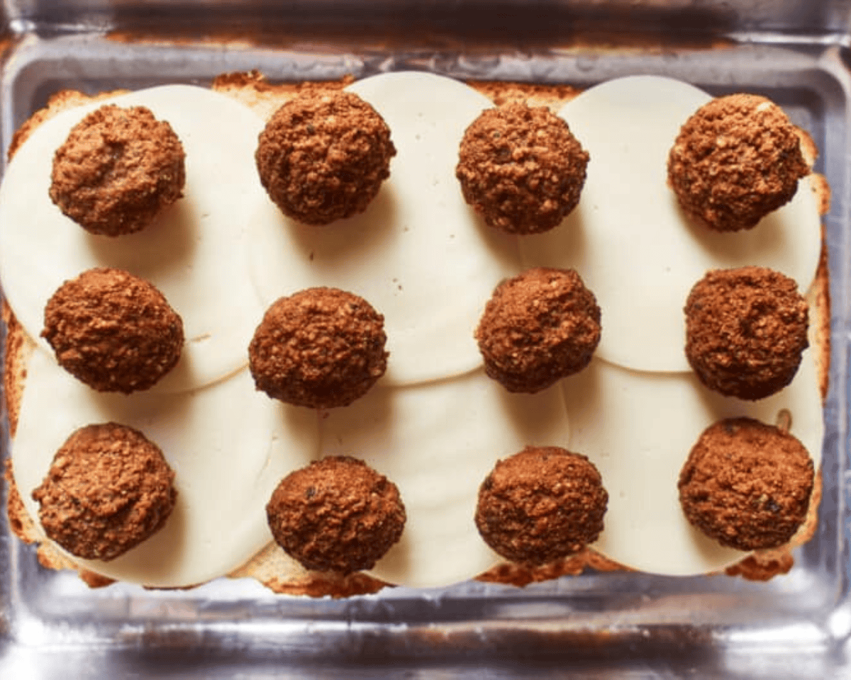 Meatballs on top of the cheese.