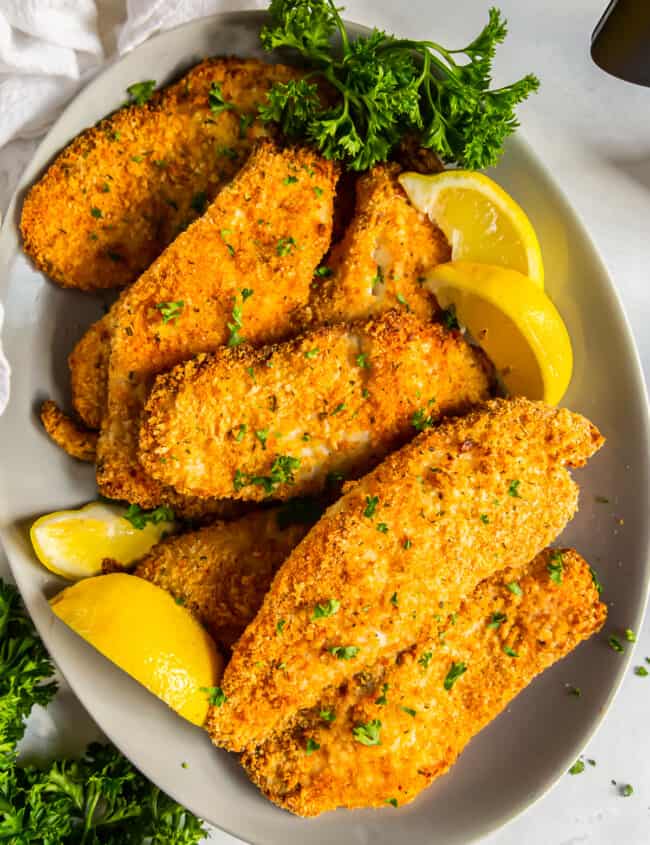 overhead image of breaded tilapia filets on a platter with lemon slices
