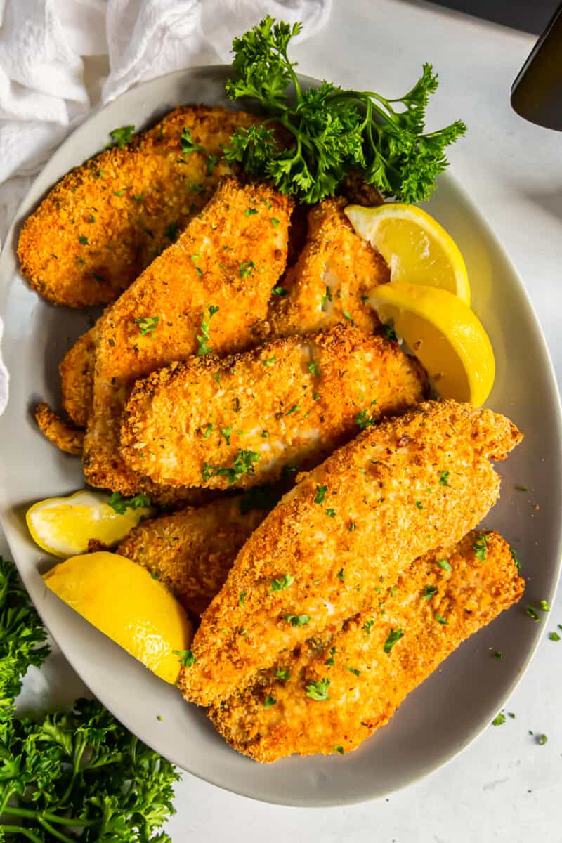 overhead image of breaded tilapia filets on a platter with lemon slices