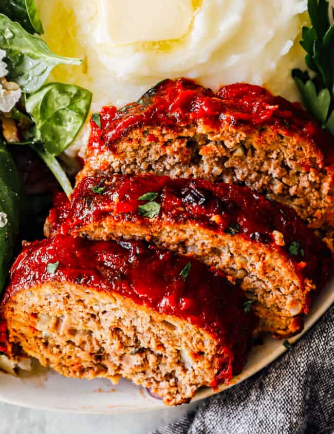 slices of air fryer meatloaf on plate with mashed potatoes and salad