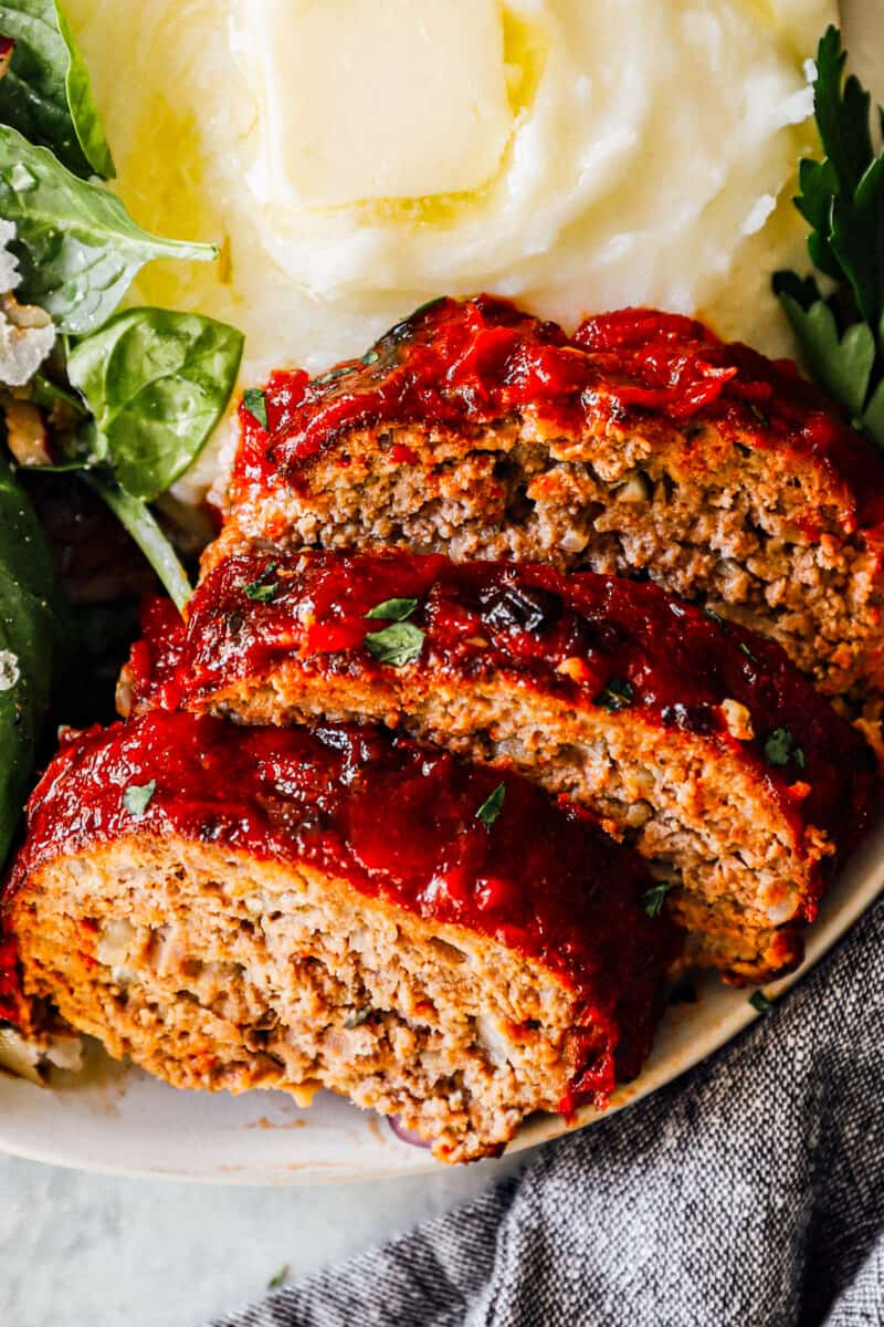 slices of air fryer meatloaf on plate with mashed potatoes and salad