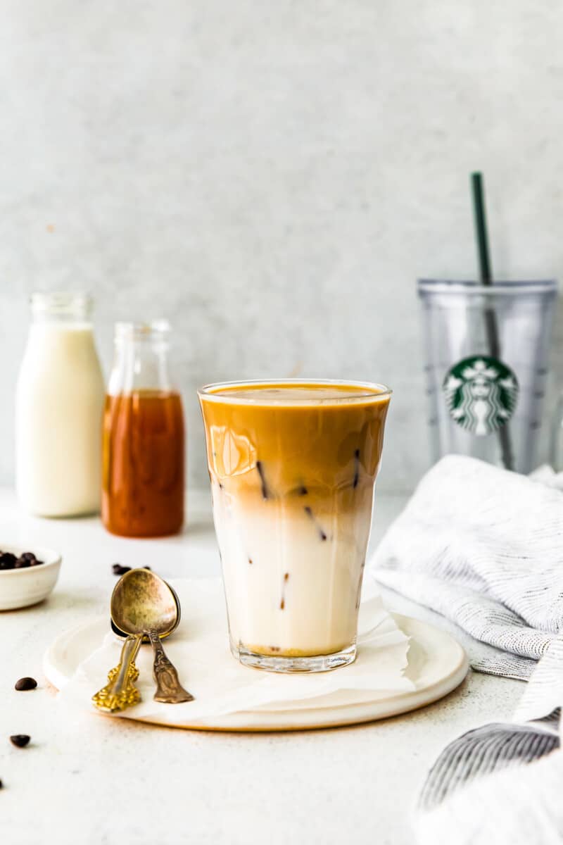 apple crisp macchiato in a clear glass on a white plate with a spoon