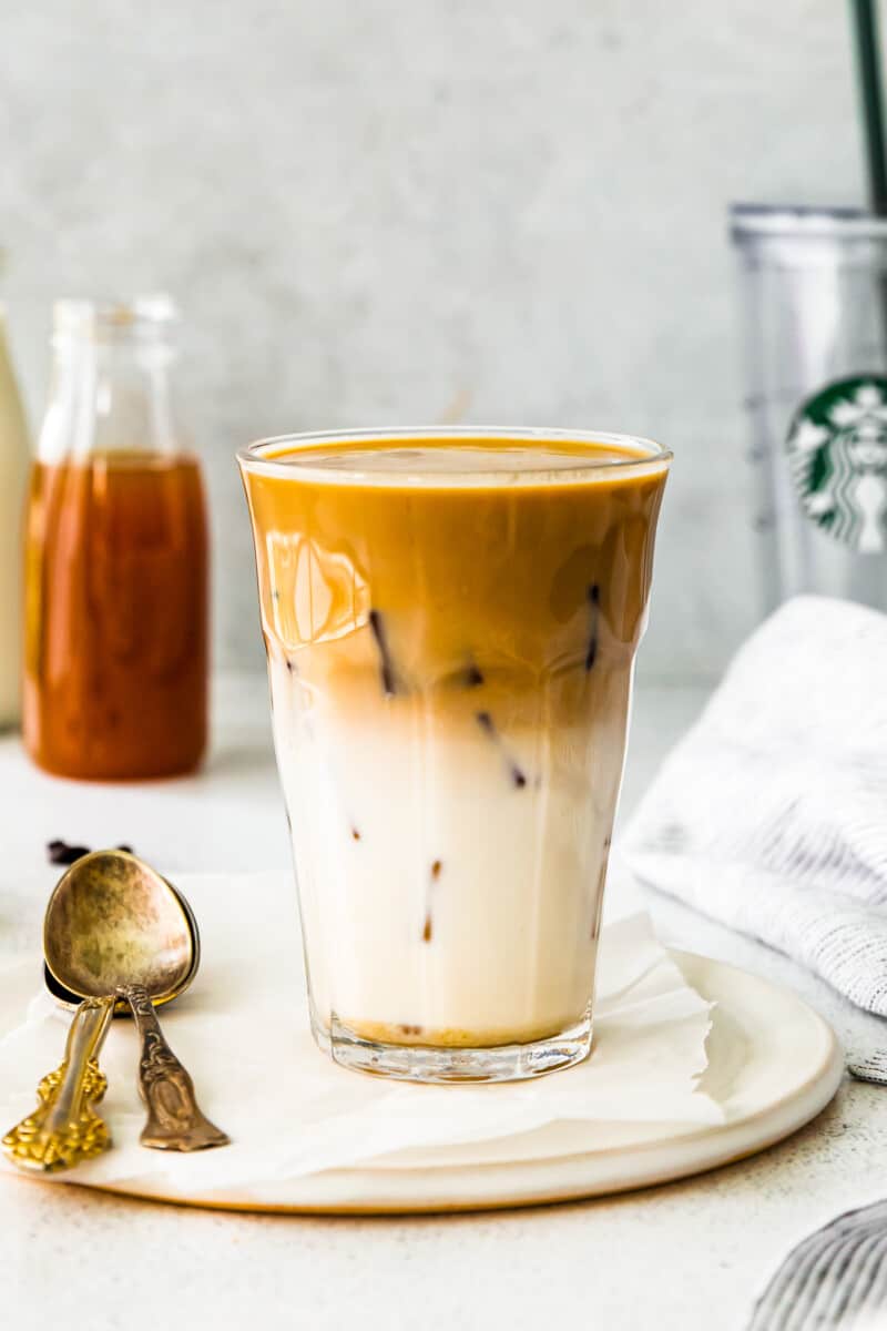 apple crisp macchiato in a clear glass on a white plate with a spoon